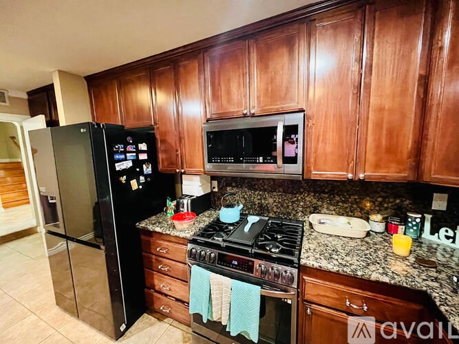 A kitchen with wooden cabinets and a black refrigerator.