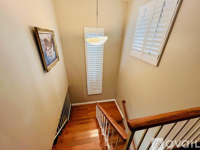 A small room with a wooden staircase and a picture on the wall.