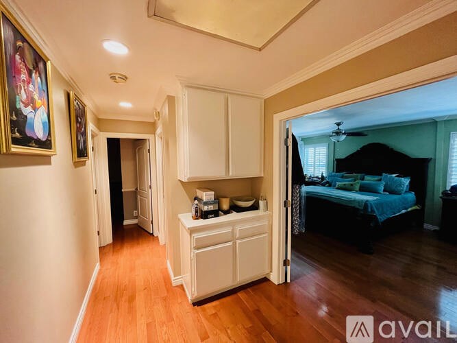 A bedroom with a bed, dresser, and a painting on the wall.