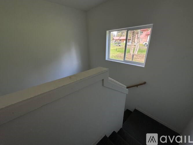 A room with a window showing a view of a tree and a building outside.