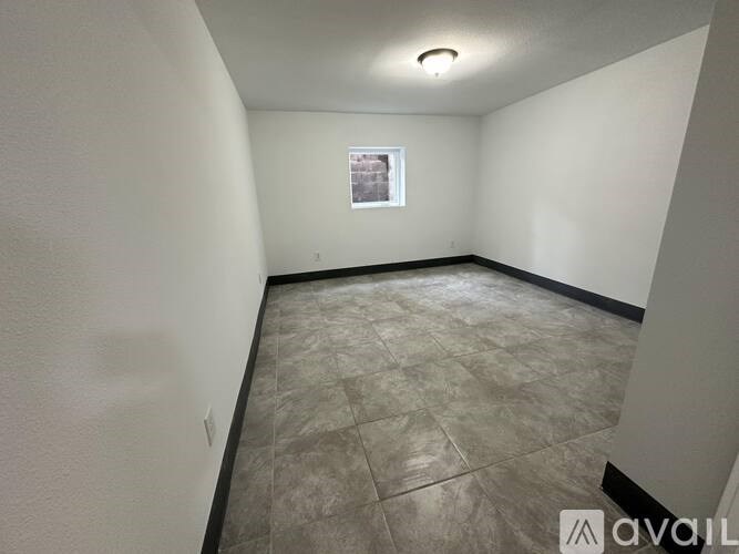 A room with tiled flooring and a window with a view of a brick wall.