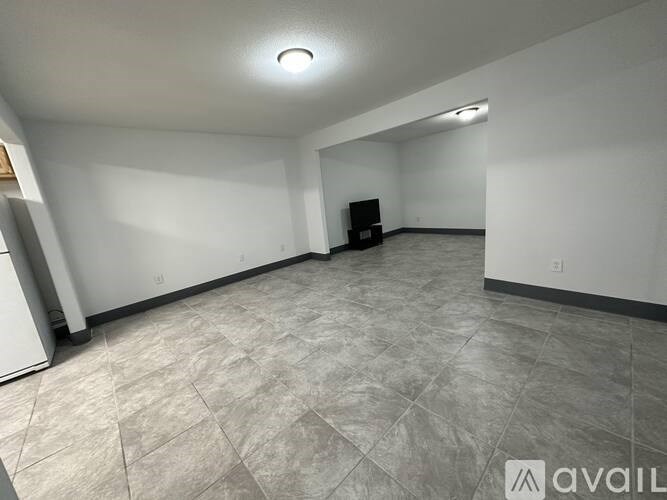 A spacious room with a tiled floor and a television in the corner.