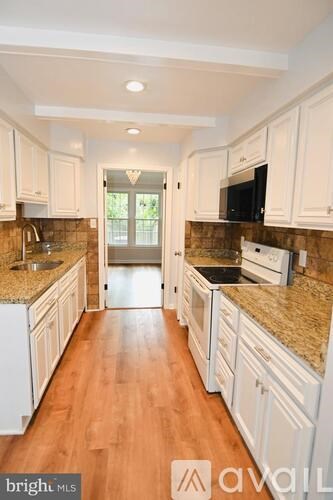 A kitchen with white cabinets and granite countertops.