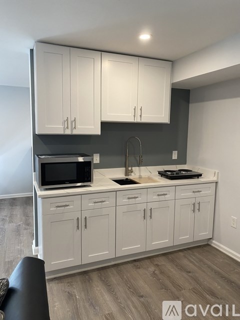 A kitchen with white cabinets and a black microwave.
