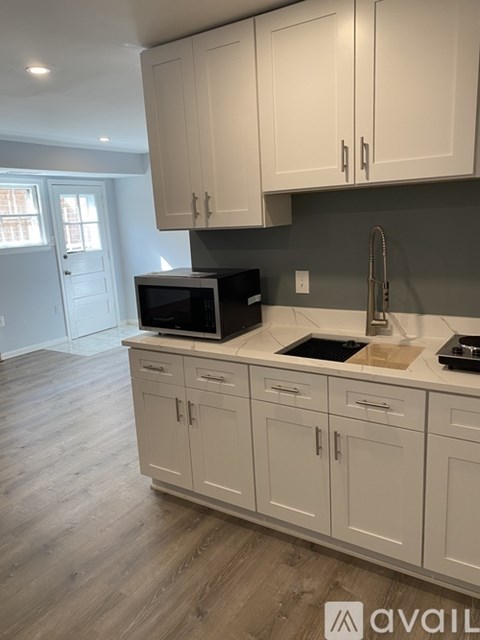 A kitchen with white cabinets and a microwave on the counter.