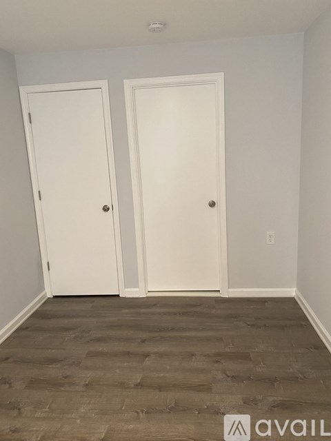 Two white doors in a room with wood flooring.