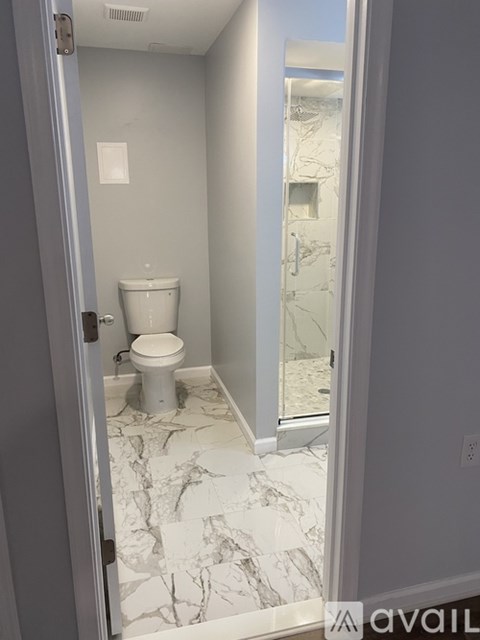 A bathroom with a toilet and marble flooring.