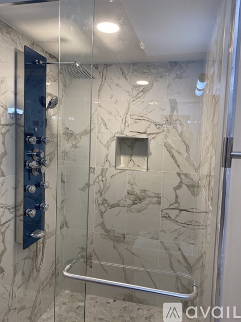 A shower with a glass door and a marble wall.