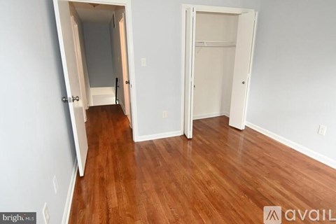A room with a wooden floor and two open doors.