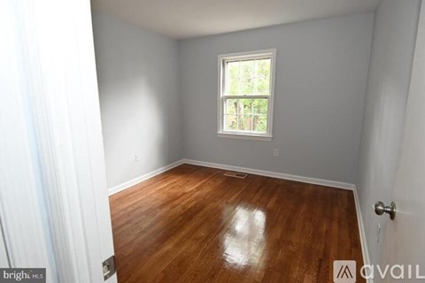 A room with wooden flooring and a window letting in light.
