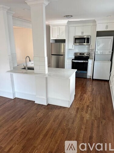 A kitchen with white cabinets and a wooden floor.