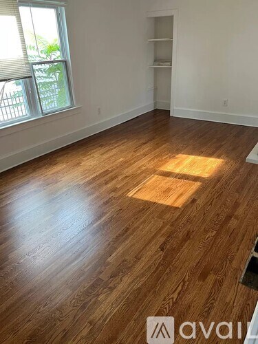 A room with wooden flooring and a window with blinds.