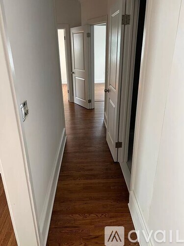 A hallway with wood floors and white walls.