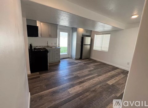 A kitchen with a black stove top oven and wooden flooring.