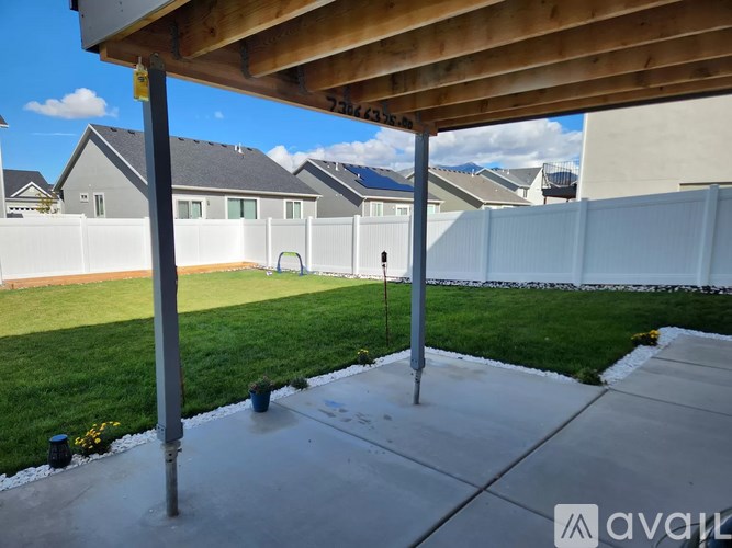 A backyard with a wooden pergola and a white fence.
