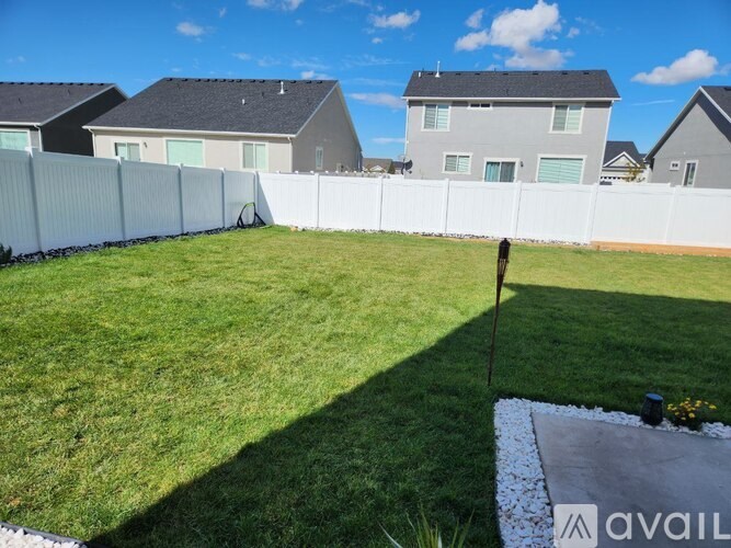 A backyard with a white fence and a well-maintained lawn.