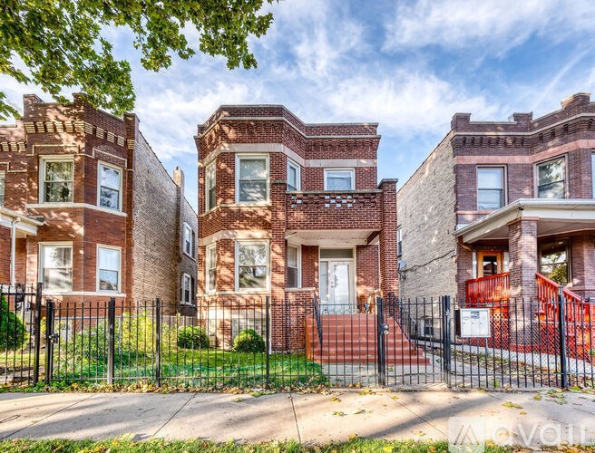 A row of red brick houses with black fences in front.