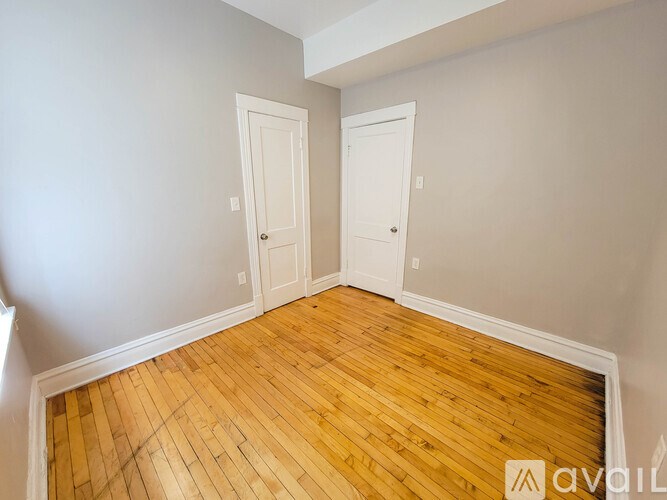 A room with wooden floors and two white doors.