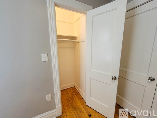 A white door is open to a small room with a wooden floor.
