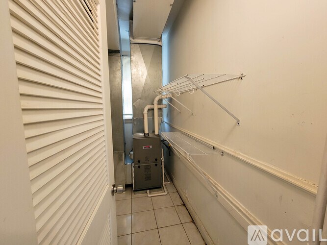 A long hallway with a metal rack on the wall and a machine in the corner.
