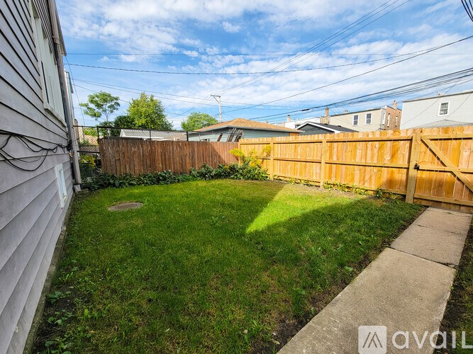 A backyard with a wooden fence and a concrete pathway.