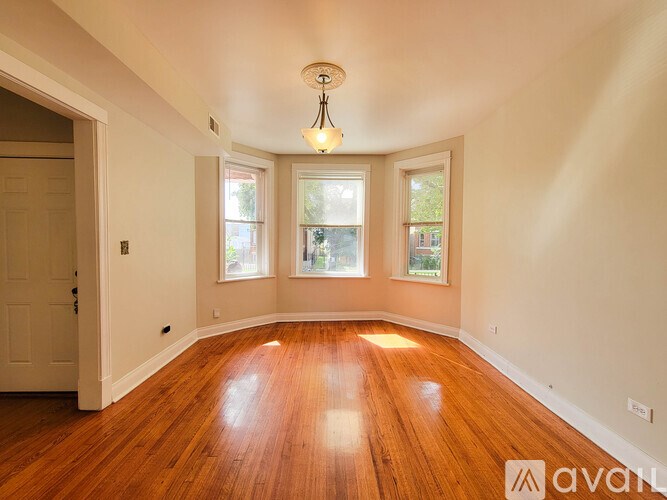 A room with wooden floors and three windows.