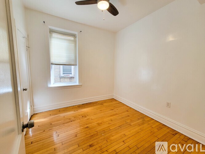 A room with wooden flooring and a window with blinds.