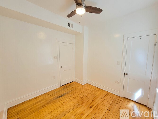 A room with a ceiling fan and wooden flooring.