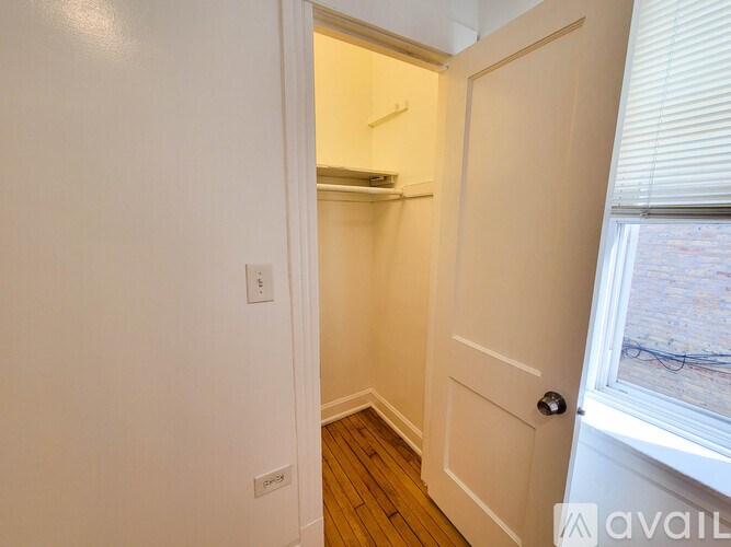 A small white closet with a door and a window.