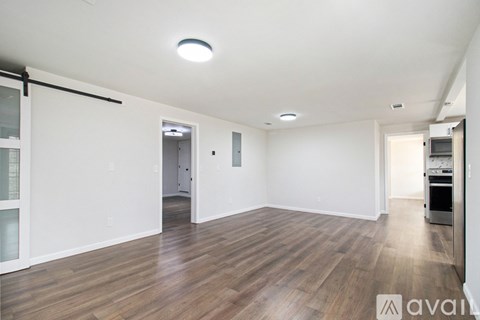 A spacious room with wooden flooring and white walls.