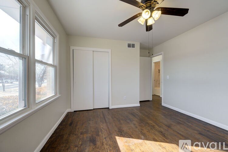 A room with a ceiling fan and wood flooring.