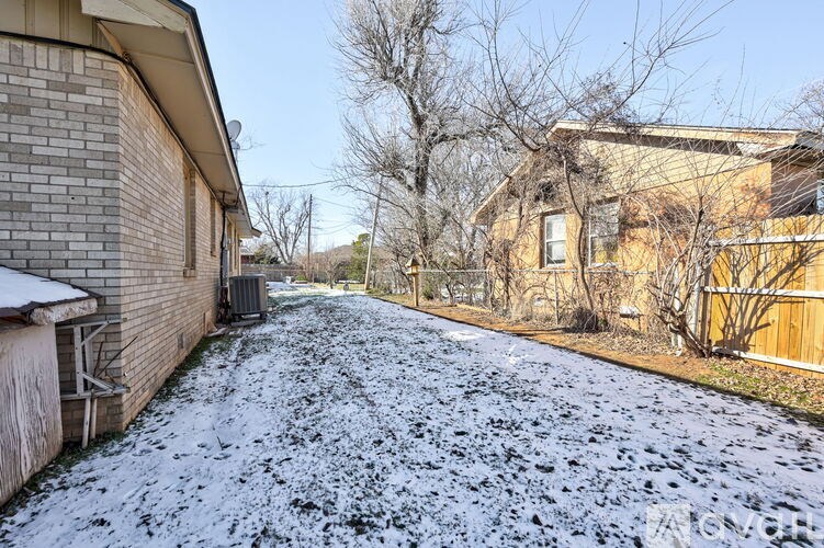A snowy residential street with houses on either side.