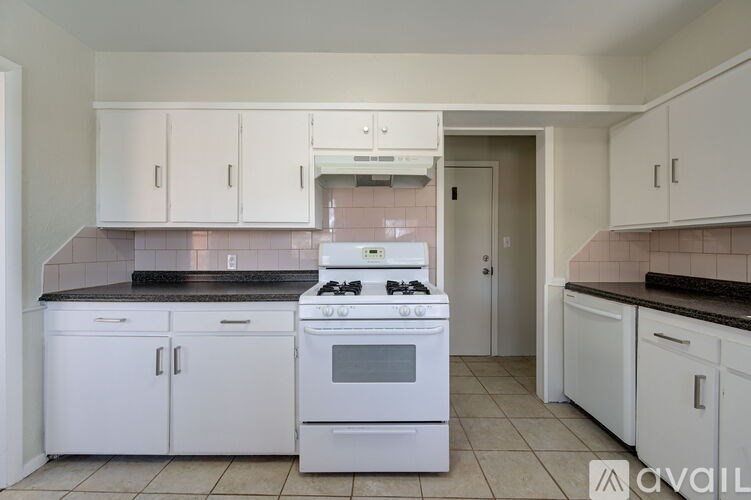A kitchen with white cabinets and a black countertop.