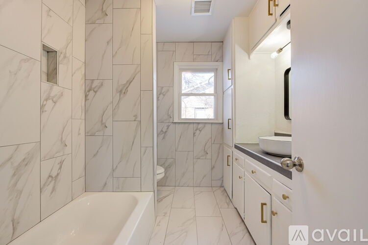 A bathroom with marble tiles and a white tub.