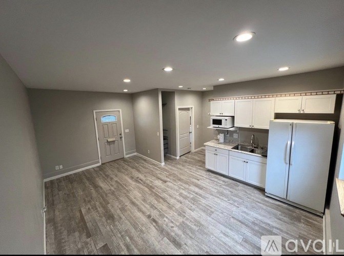 A kitchen area with a refrigerator, sink, and cabinets.