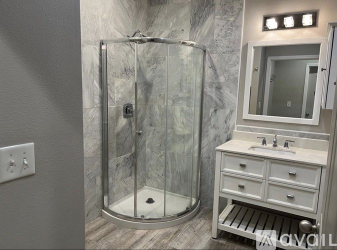 A bathroom with a marble wall and a walk-in shower.