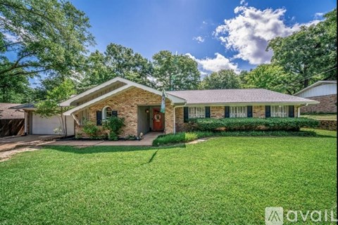 A house with a front yard and a tree in the background.