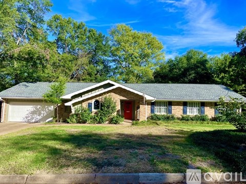 A house with a red door is surrounded by greenery.