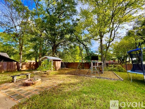 A backyard with a trampoline and a swing set.
