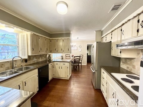 A kitchen with white cabinets and a wooden floor.