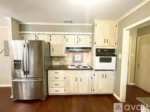 A kitchen with white cabinets and a silver refrigerator.