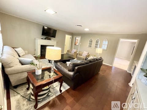 A living room with a couch, a chair, a coffee table, and a television.