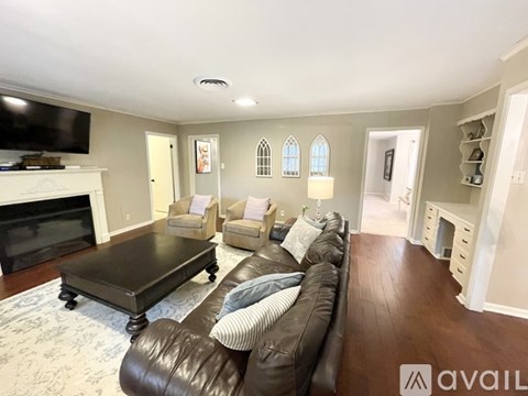 A living room with a brown leather couch and a fireplace.