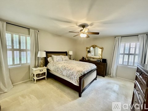 A bedroom with a large bed, a dresser, and a mirror.
