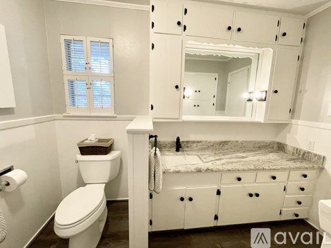 A white bathroom with a toilet, sink, and mirror.
