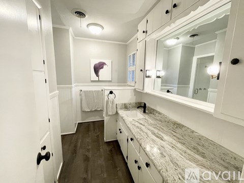 A bathroom with a marble countertop and white cabinets.