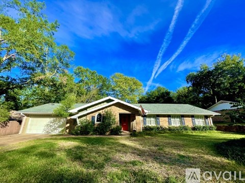 A house with a green lawn and trees in the background.