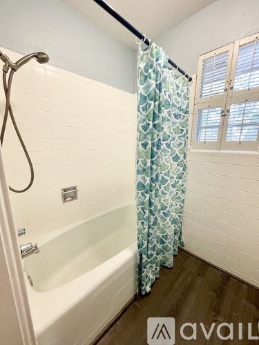 A bathroom with a white tub and a shower curtain with a blue pattern.