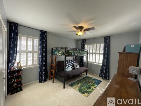 A room with a bed, a chair, and a ceiling fan.