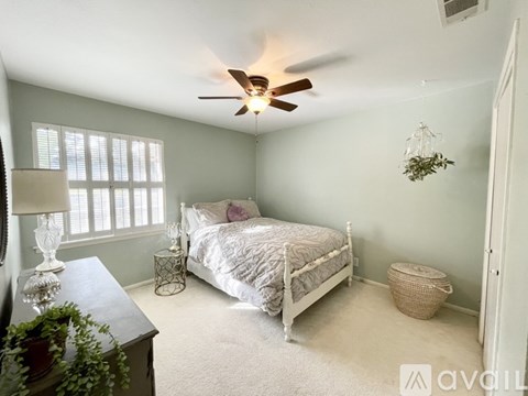 A bedroom with a bed, nightstand, and window.